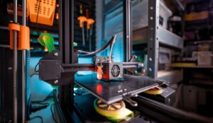 Close-up of a 3D printer operating in a workshop, showing the print head and build platform during additive manufacturing.