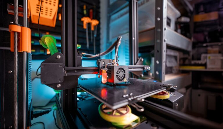 Close-up of a 3D printer operating in a workshop, showing the print head and build platform during additive manufacturing.