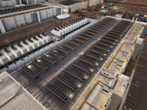 Aerial view of a large data-center roof with extensive rows of cooling equipment and supporting infrastructure.