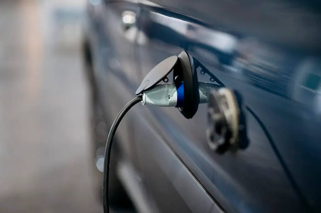 Close-up of an electric-vehicle charging connector plugged into a blue car.