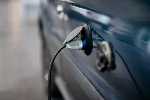 Close-up of an electric-vehicle charging connector plugged into a blue car.