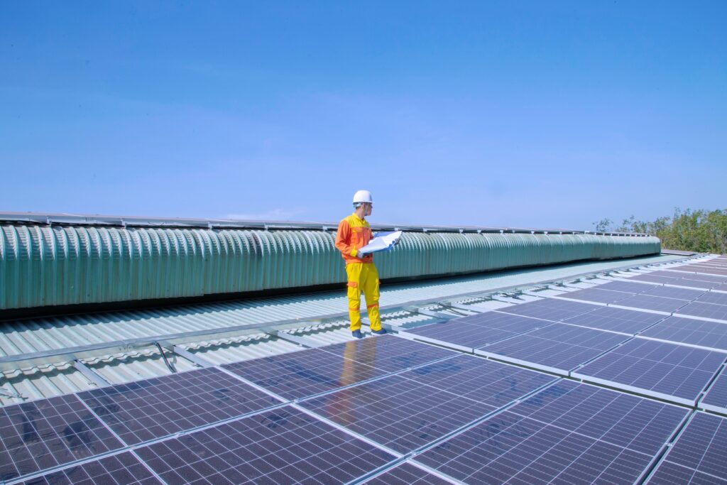 Technician examining rooftop solar panels; illustrative PV end-equipment context for inverter control ICs, not a specific inverter, IC architecture or customer installation.