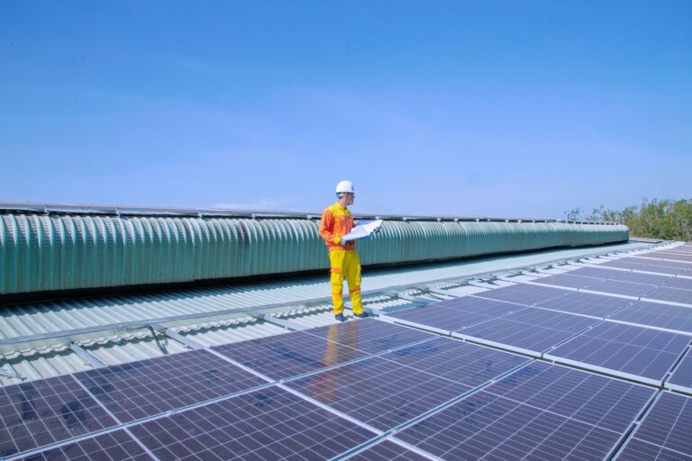 Technician examining rooftop solar panels; illustrative PV end-equipment context for inverter control ICs, not a specific inverter, IC architecture or customer installation.