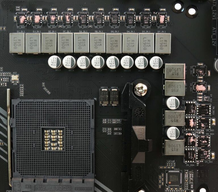 Close-up of a modern motherboard voltage-regulator module with repeated power-stage packages, inductors and capacitors beside the processor socket.