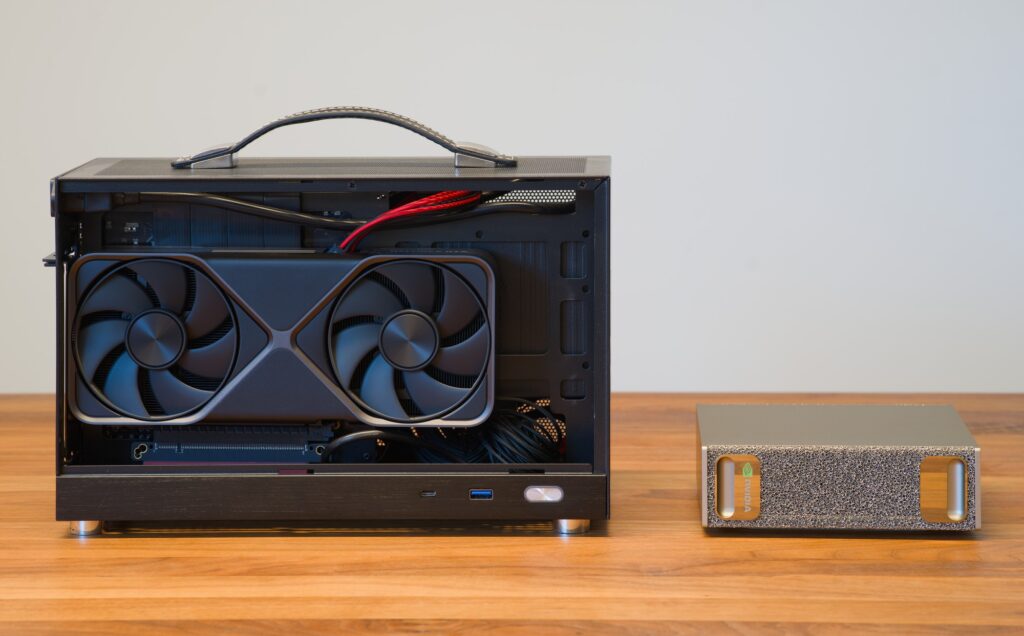 Open compact desktop computer with a graphics card beside an NVIDIA DGX Spark desktop AI system