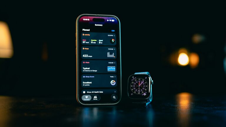 Smartphone displaying a health app beside a smartwatch on a dark tabletop.